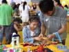 7月12日，一名小朋友和家长在北京玩博会上玩乐高玩具。新华社记者 罗晓光 摄
