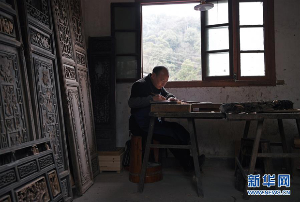 在江西省婺源县思口镇漳村，俞友鸿在查看一处民宿建筑上残损的木雕作品（3月19日摄）。