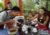 8月11日，游客在北京世园会云南园参观时准备品尝普洱茶。