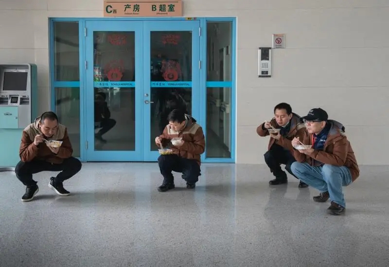 2月21日，摄影小分队在为医务工作者紧张拍摄的间隙，在走廊吃盒饭。潘松刚 摄