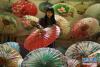 12月20日，在贵州省赤水市大同镇，一名工人在给伞面抹桐油。新华社发（王长育 摄）