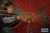 12月19日，在贵州省赤水市大同镇，赤水油纸伞制作技艺传承人李珍霞在裱伞面。新华社发（王长育 摄）