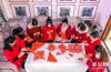 1月17日，岳红霞（右四）带领工作室学员创作“金牛送福”剪纸。