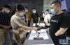 7月8日，参观者与使用仿生机械手的展方工作人员握手。新华社记者 方喆 摄