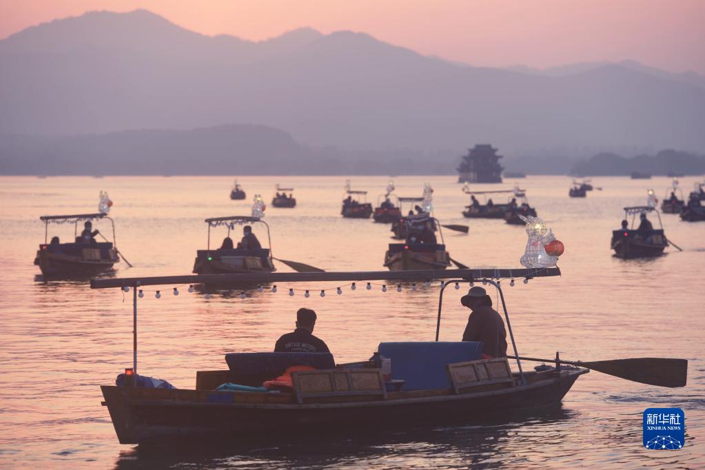 1月11日，市民游客乘坐装有“玉兔灯”的人力手划船泛舟杭州西湖。