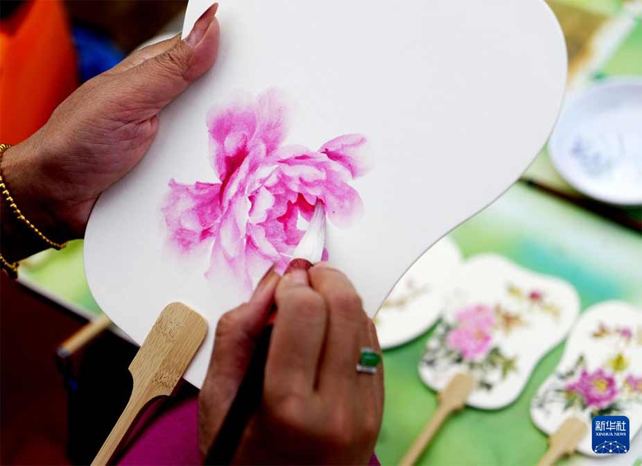 4月17日，在河南省洛阳市隋唐城遗址植物园，工作人员在绘制牡丹主题工艺扇子。 新华社记者 李嘉南 摄
