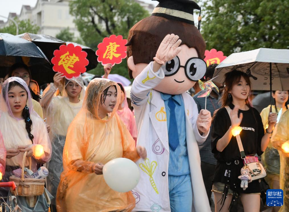6月21日，农机花车队伍在华中农业大学校园里冒雨巡游。新华社记者 程敏 摄