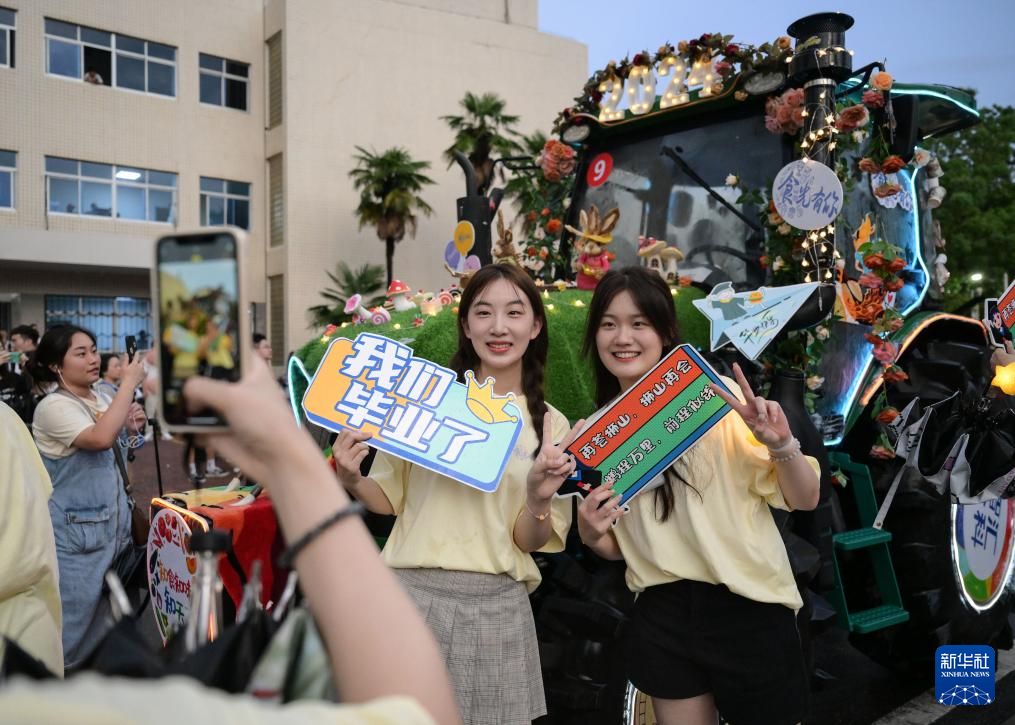 6月21日，华中农业大学学生在农机花车前拍照留念。新华社记者 程敏 摄