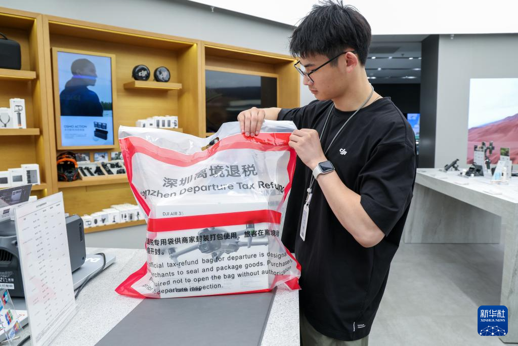 4月30日，在深圳万象城大疆门店，员工使用标准密封袋为顾客选购的产品进行离境退税“一单一包”打包。新华社记者 毛思倩 摄