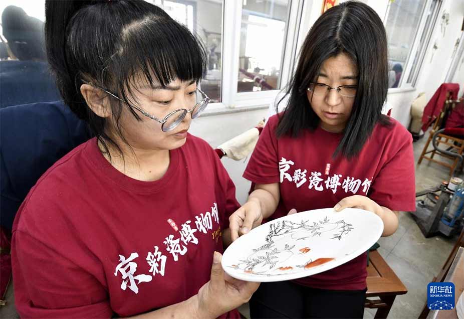 北京三级工艺美术大师、京彩瓷第五代传承人杨雪（右）在指导青年技师绘画（6月18日摄）。新华社记者 李欣 摄