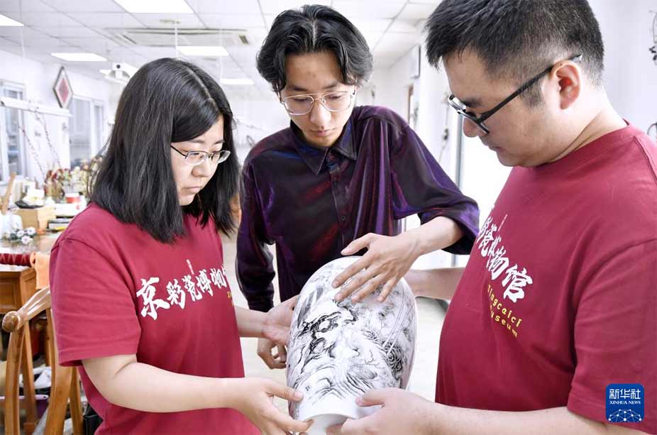 北京三级工艺美术大师、京彩瓷第五代传承人杨雪（左一）检验京彩瓷质量（6月18日摄）。新华社记者 李欣 摄